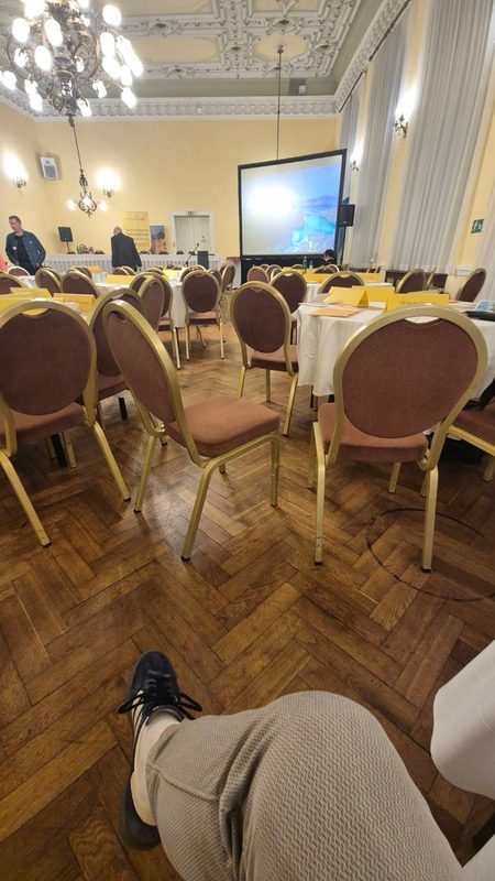 Festsaal mit Kronleuchter, runden Tischen und Leinwand vor Beginn der Marienbader Gespräche