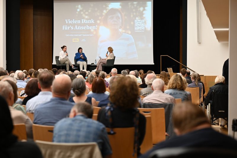 Filmgespräch auf der Bühne des großen Saals im Sudetendeutschen Museum: Michael Eibl, seine Oma und Moderatorin Eva Haupt vor vollem Publikum, auf der Leinwand „Vielen Dank für’s Ansehen!“